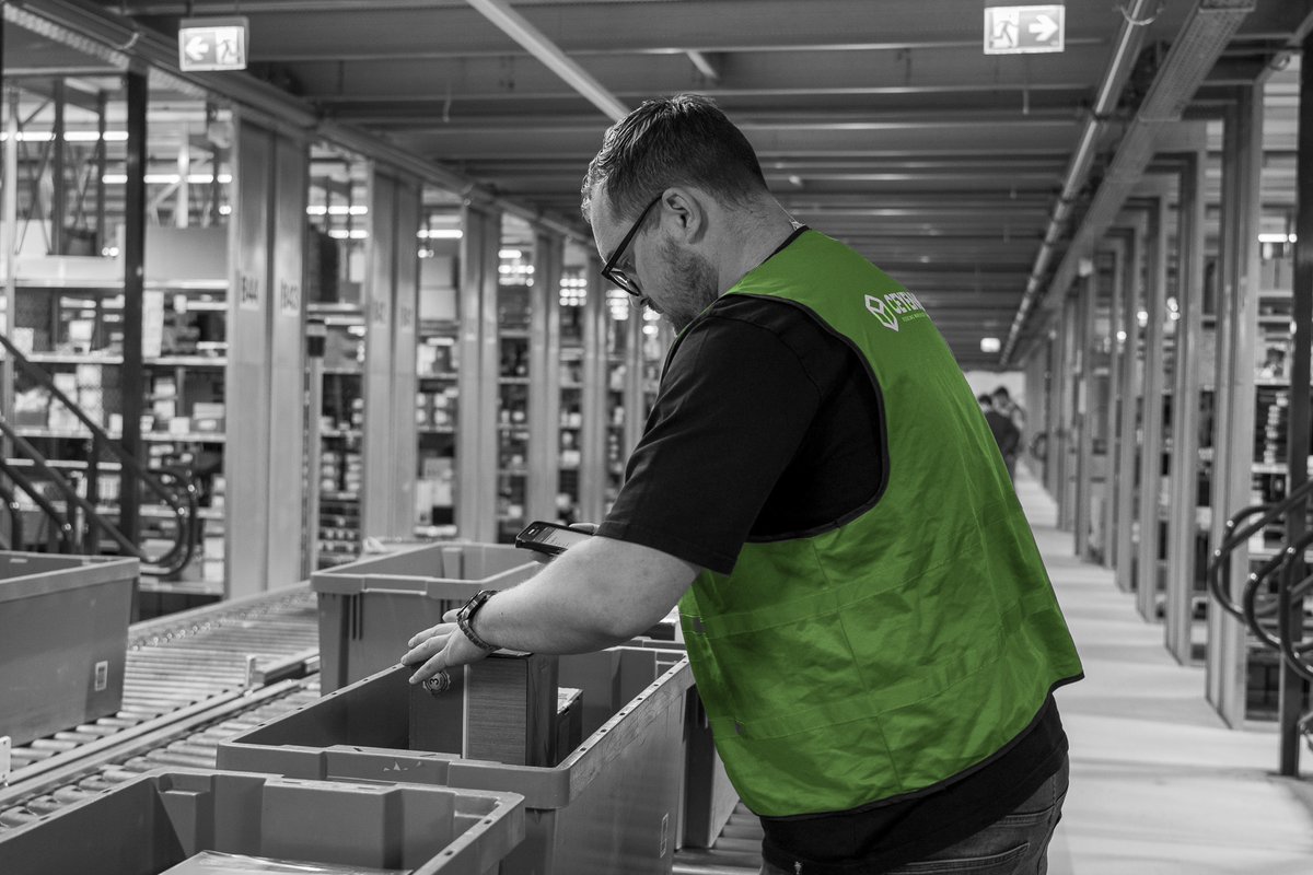 medewerker-sorteert-onderdelen-in-bakken-zwart-wit
